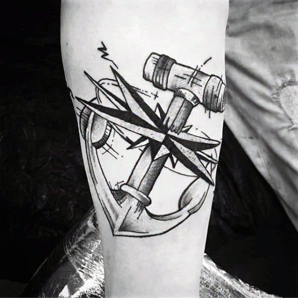 Black and white anchor tattoo with a compass and intricate nautical design on a person's arm