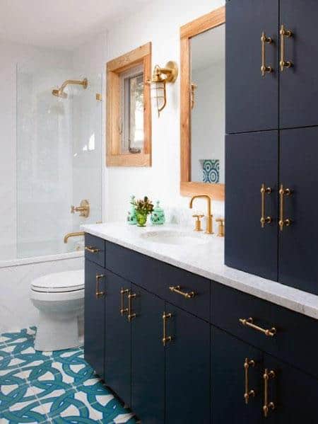 Navy blue bathroom vanity with gold hardware, white countertop, and patterned floor.
