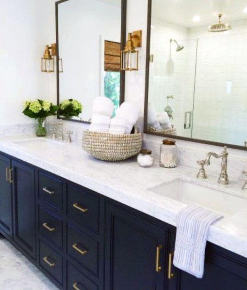 Navy blue double vanity with white countertops, gold hardware, and glass shower.