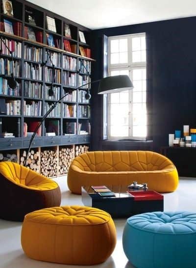 Colorful modern living room with armchairs, a bookshelf, and a large window