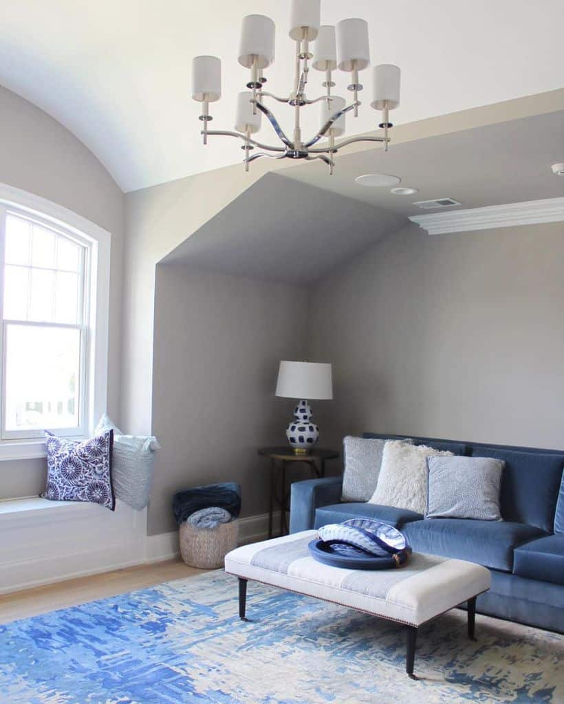 Elegant living room with navy sofa, patterned blue rug, and white chandelier.