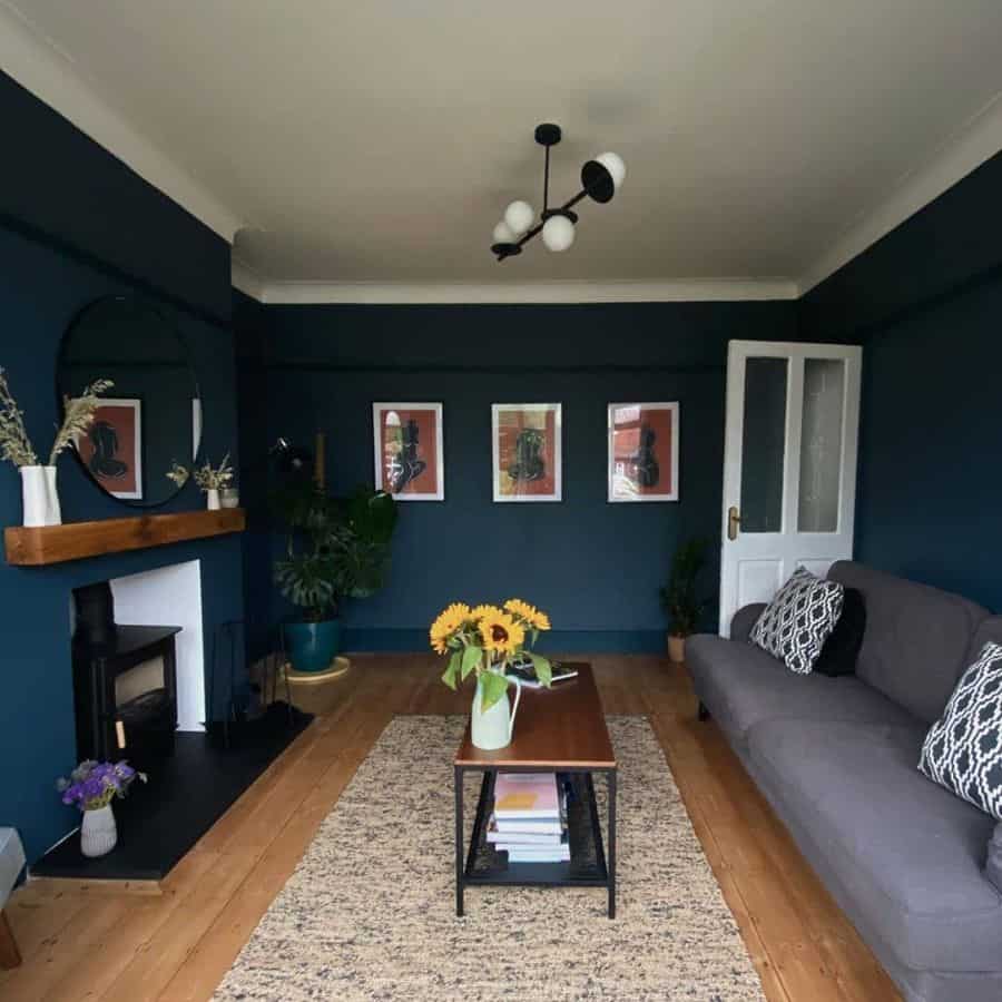 Dark blue living room with grey sofa, wooden coffee table, and modern wall art.