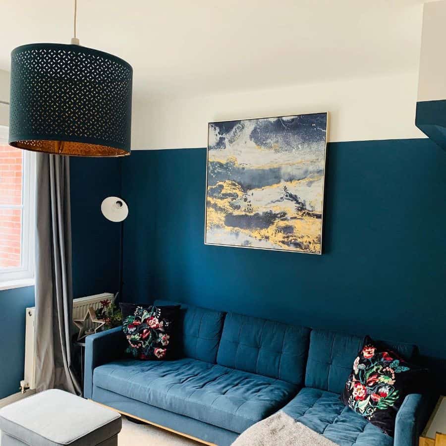 Modern navy blue living room with blue sofa, abstract wall art, and patterned pillows.