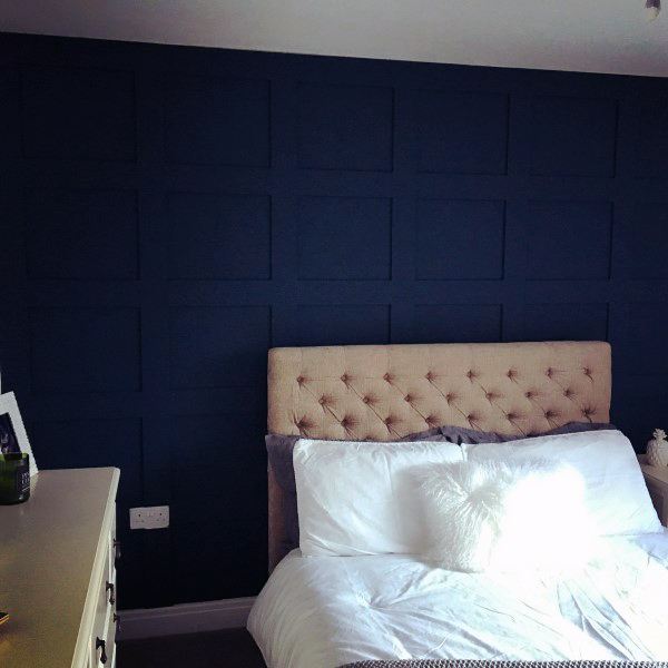 Elegant bedroom with a tufted headboard and a navy blue feature wall adding depth and texture.