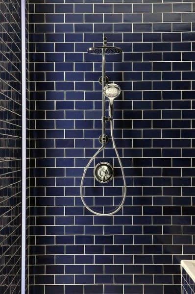 Navy blue beveled subway tile shower with chrome fixtures and rainfall showerhead.