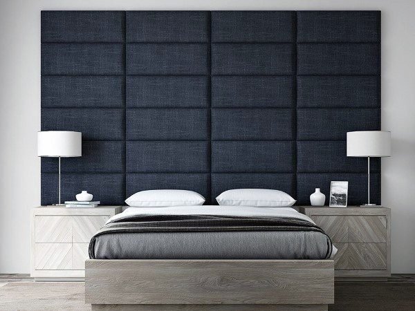 Modern bedroom with large navy upholstered headboard, gray bed, and sleek nightstands.