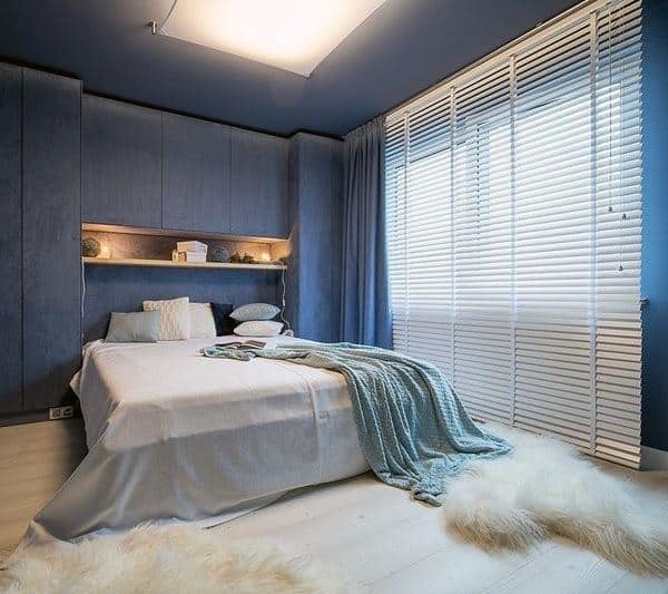 Modern navy bedroom with sleek built-in cabinets, soft bedding, and cozy fur rugs.