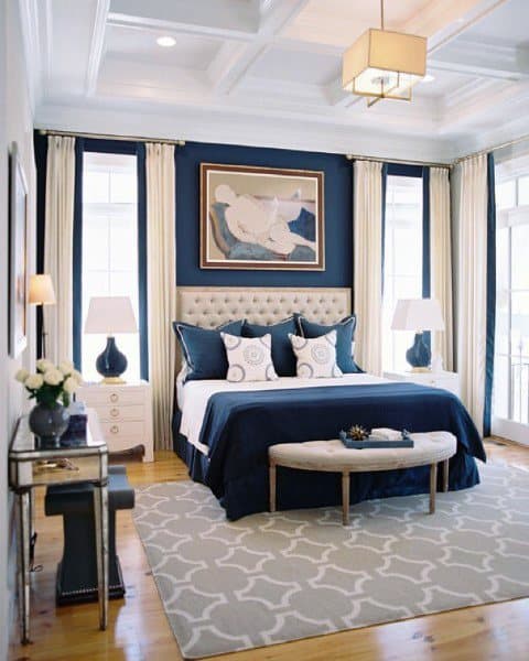 Navy and white bedroom featuring a tufted headboard, patterned pillows, and elegant decor.