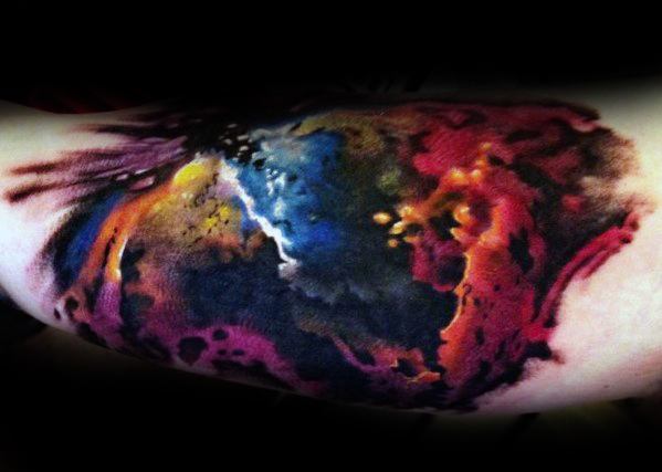 Vivid watercolor-style nebula tattoo with cosmic hues of blue, red, yellow, and black on skin
