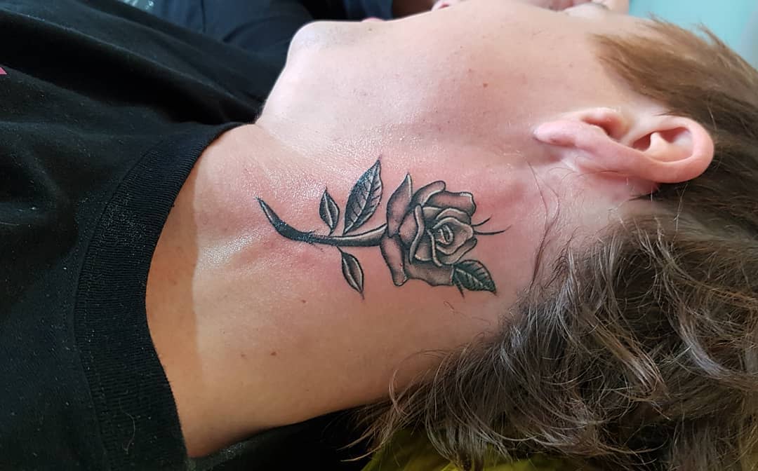 Neck tattoo of a detailed black and gray rose on a woman
