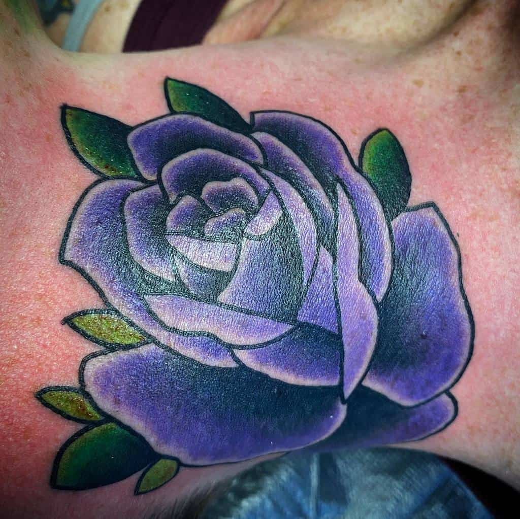 A purple rose tattoo with green leaves on skin
