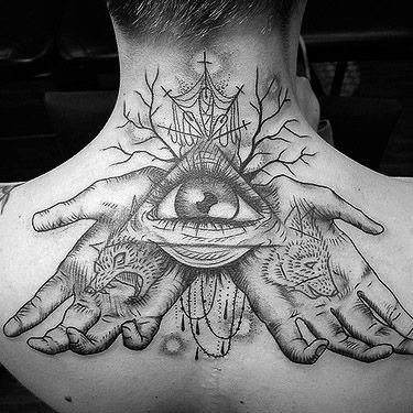 Tattoo on back depicting hands holding an eye, trees, and faces of a wolf and a fox
