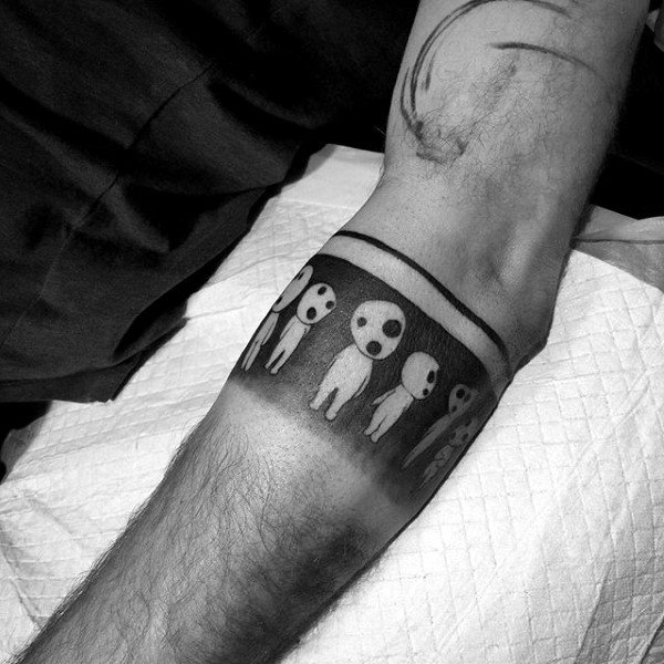 Black band tattoo with ghost-like figures in the middle on a person's forearm