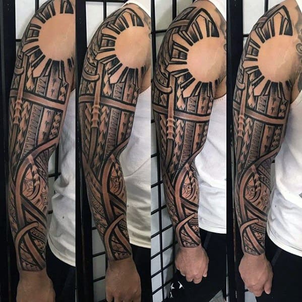 Filipino sun full-sleeve tattoo with bold tribal rays on the shoulder, extending into intricate geometric patterns and flowing bands down to the wrist.