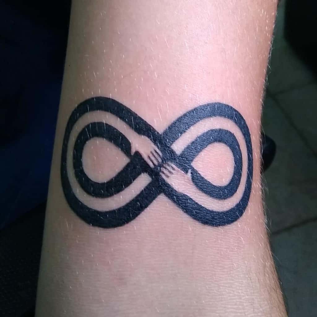A powerful infinity tattoo featuring two hands grasping each other, symbolizing an eternal bond or connection.