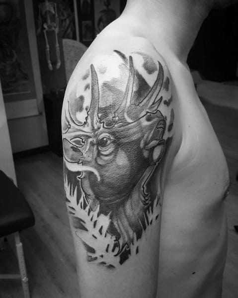 Realistic black and grey elk tattoo on the upper arm, featuring bold shading, intricate details, and a dynamic background for a striking design.