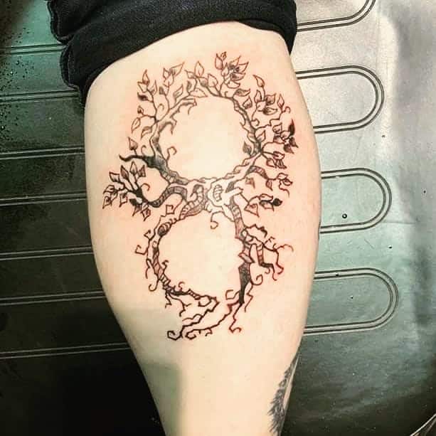 The tattoo features two intertwined trees that form the shape of a semicolon, symbolizing resilience and growth.