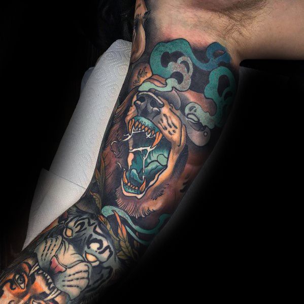 Neo-traditional bear tattoo sleeve featuring a roaring bear with bold shading, swirling teal smoke, and intricate tiger details below.