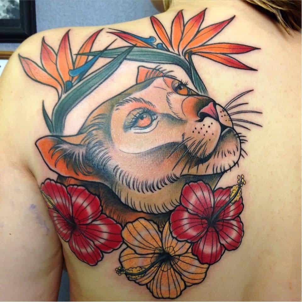 Colorful lioness tattoo on the upper back, featuring bold shading, hibiscus flowers, and bird of paradise for a vibrant, tropical look.