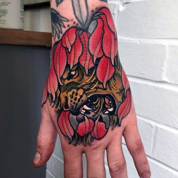 Neo-traditional lion hand tattoo with bold red petals framing the face, blending fierce expression with floral elegance.