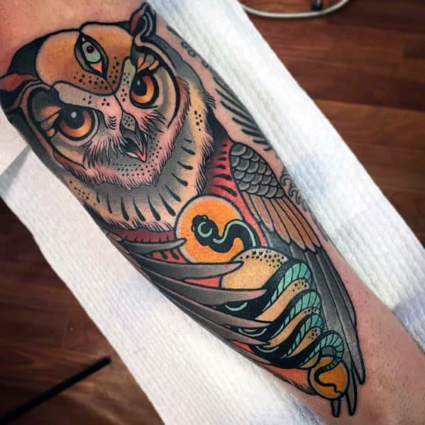 Neo-traditional owl tattoo with bold shading, a third eye, and a yin-yang symbol, blending mysticism and intricate detailing on the forearm.