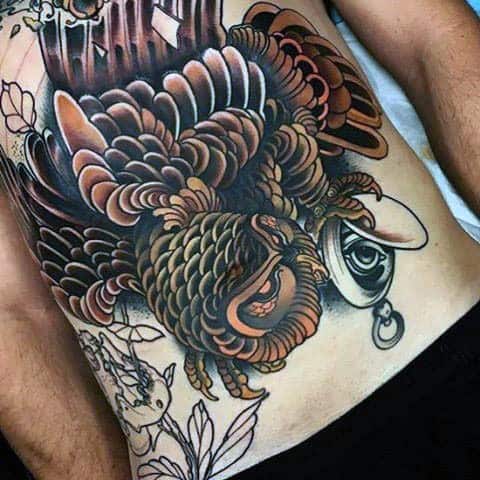 Neo-traditional owl tattoo with bold shading, intricate feather details, and a mystical eye pendant, creating a dramatic and dynamic ribcage design.