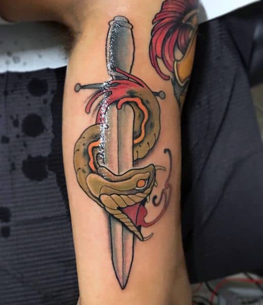 Neo-traditional tattoo of a fierce snake coiled around a dagger, with bold shading and red accents adding depth and intensity to the design.