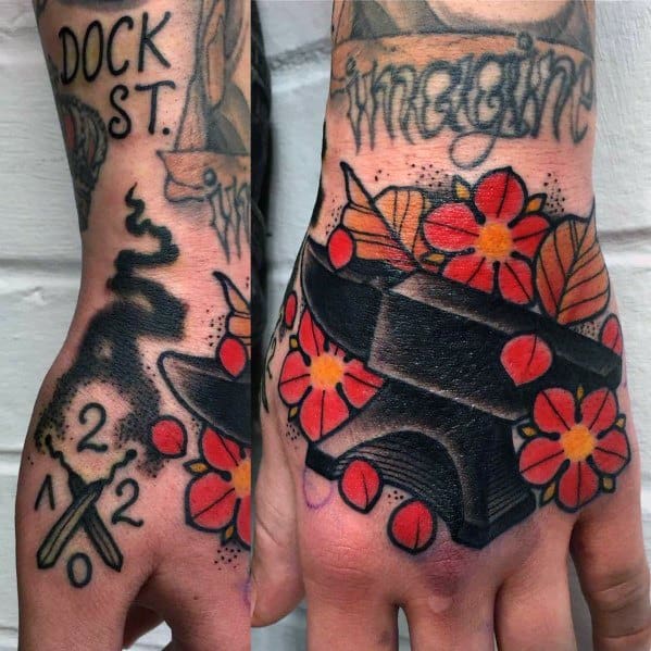 Traditional hand tattoos featuring a bold black anvil surrounded by red flowers and leaves, with smoke, spark effects, and crossed tools for added symbolism.