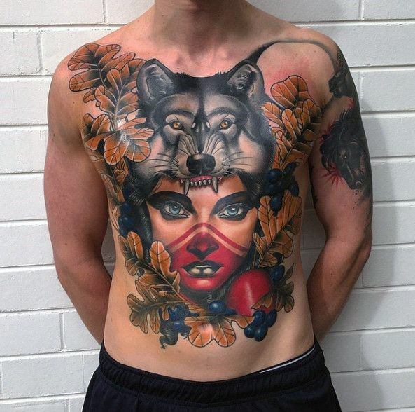 Neo-traditional chest tattoo of a fierce woman with tribal markings, a wolf headdress, autumn leaves, dark berries, and a bold color palette.
