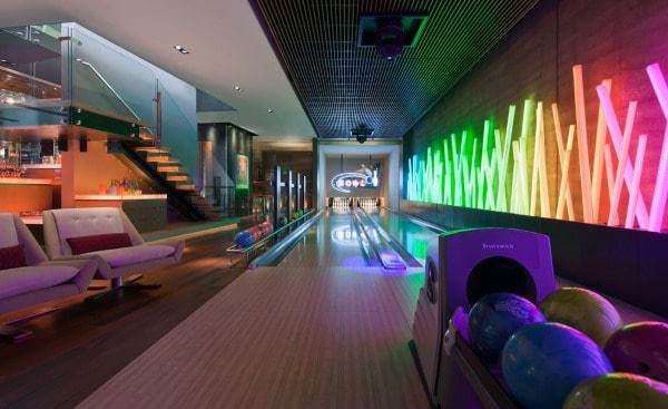 A modern home bowling alley with colorful neon lights and a cozy seating area