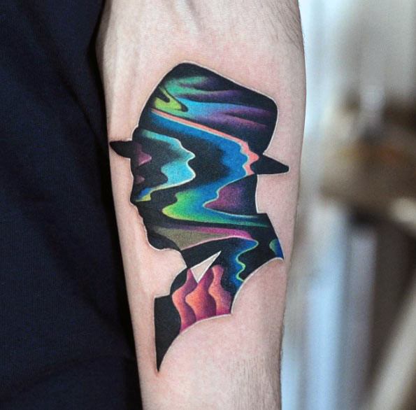 Silhouette tattoo of a man in a hat filled with colorful, wavy glitch patterns, blending mystery with digital surrealism.