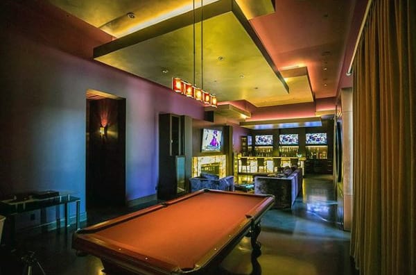 Luxury lounge with a pool table, ambient lighting, and multiple TV screens on the wall
