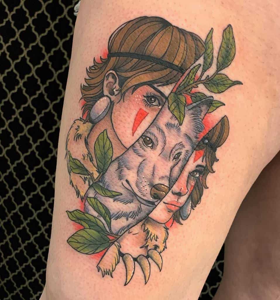 Colorful tattoo on the upper arm featuring a split design showing a character wearing a wolf mask on one side and a wolf's face on the other, with vibrant red and green accents from leaves and fur details.