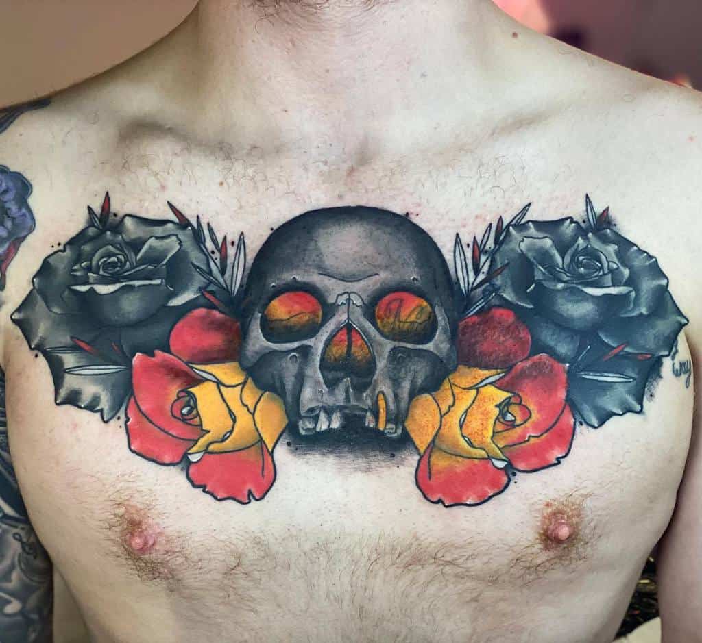 Bold chest tattoo of a dark skull with fiery eyes, surrounded by black and vibrant red-yellow roses, blending realism and neo-traditional style.