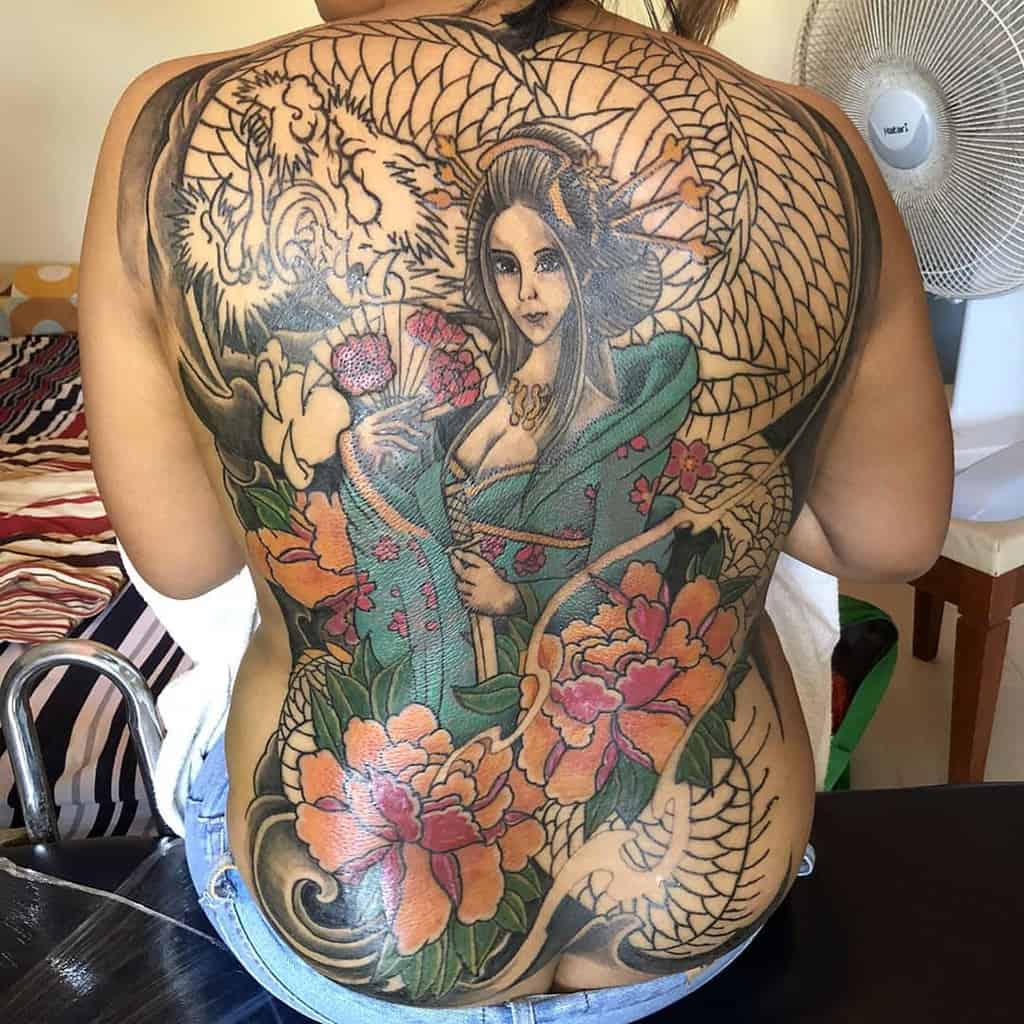 Full-back Japanese-style tattoo of a Geisha in a flowing green kimono, surrounded by vibrant peonies, a coiling dragon, and intricate patterns.