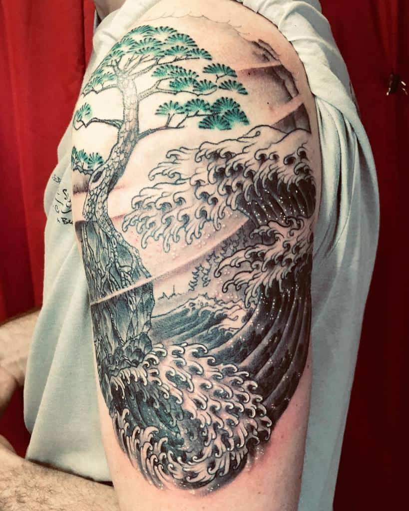 Japanese-inspired tattoo featuring a powerful ocean wave, a rocky cliff, and a detailed tree with green foliage