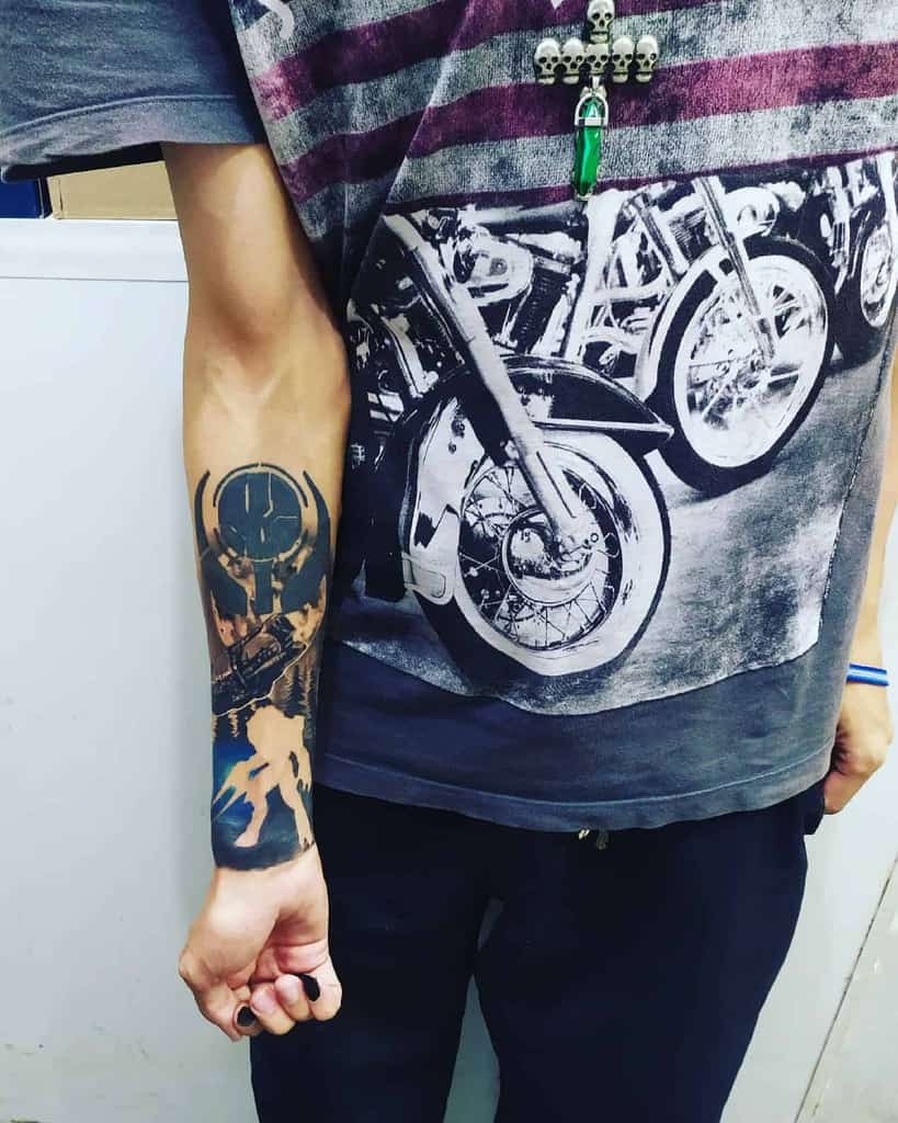 Dark and dynamic Halo tattoo featuring a bold UNSC emblem, Master Chief in action, and a detailed battle scene, inked on the forearm.