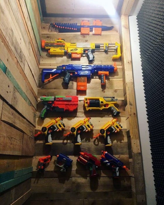 Wall-mounted display of colorful Nerf toy guns on a wooden panel.