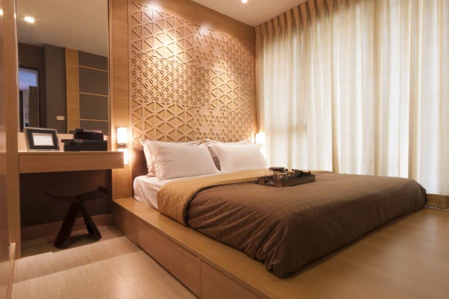 Hotel bedroom with neutral colors, platform bed, and decorative wood accent wall.