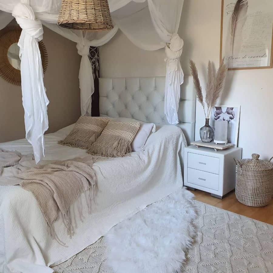 Neutral bohemian bedroom with canopy bed, textured pillows, pampas grass, and a wicker basket