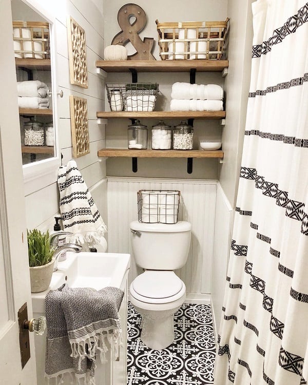 Rustic farmhouse bathroom with open wooden shelves, patterned floor tiles, and striped decor.