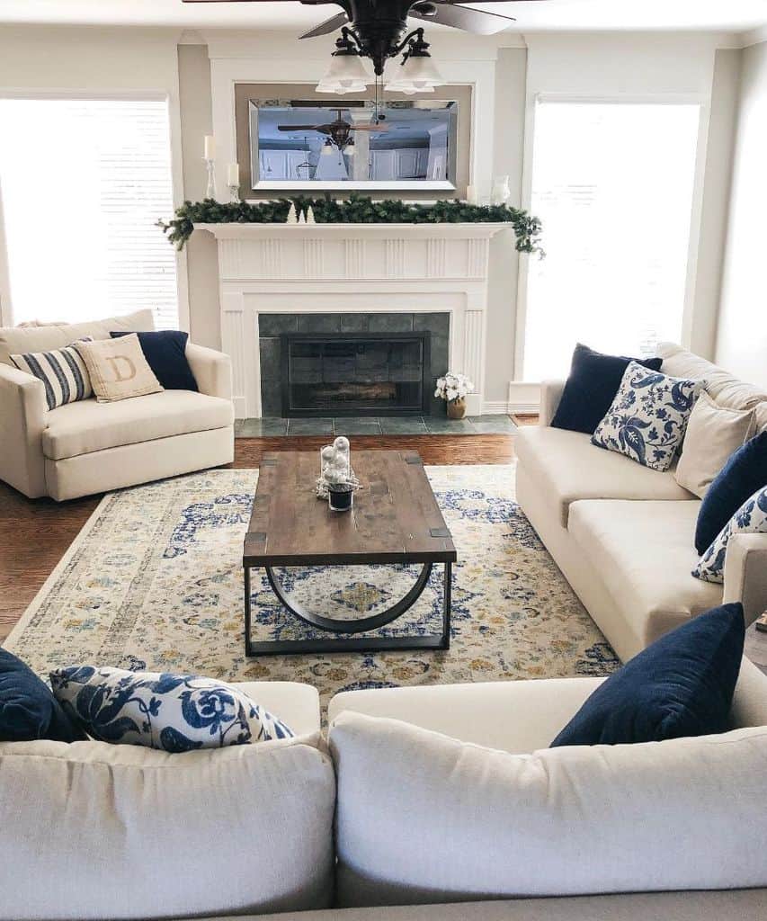 neutral modern farmhouse living room fireplace white sofa blue pillows wall mirror over mantle wood table