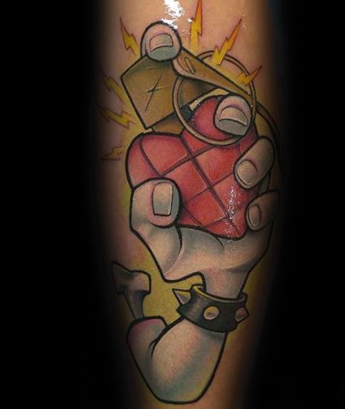 Cartoon-style tattoo of a spiked wristband hand gripping a red heart grenade with yellow lightning bolts, inspired by *American Idiot*.