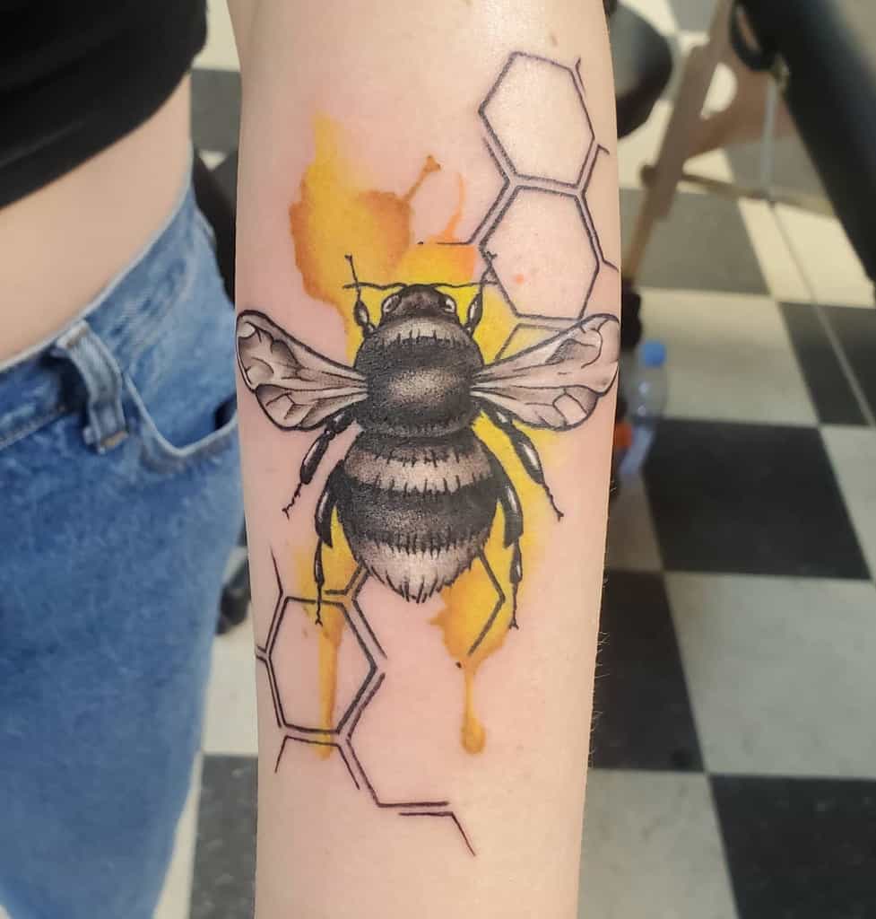 Tattoo of a bee, with honeycomb and yellow ink splashes