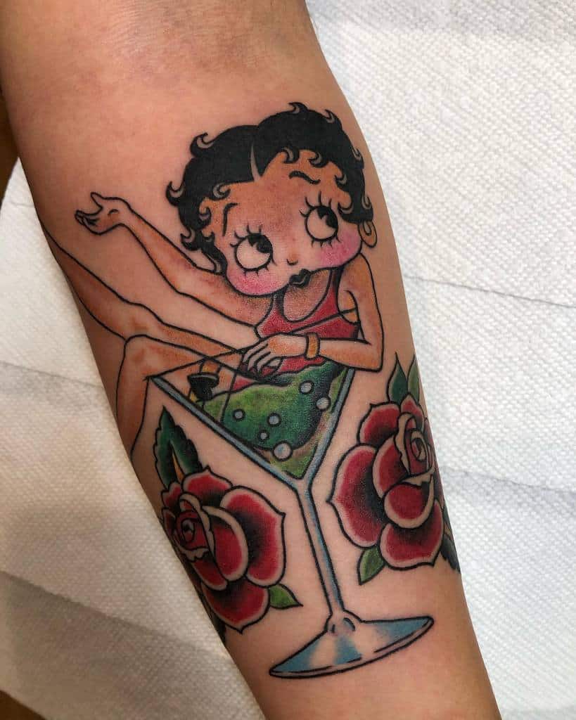 Retro-style Betty Boop tattoo lounging in a martini glass, surrounded by vibrant red roses