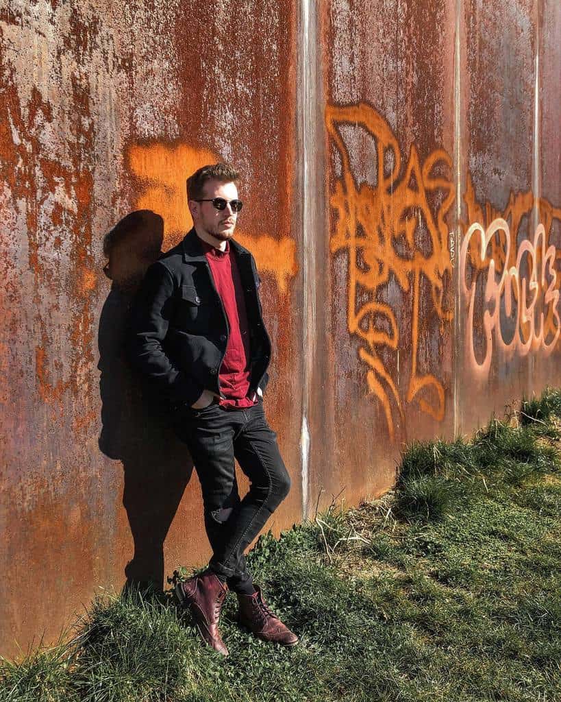 black jacket under red shirt black pants with cool boots and shades