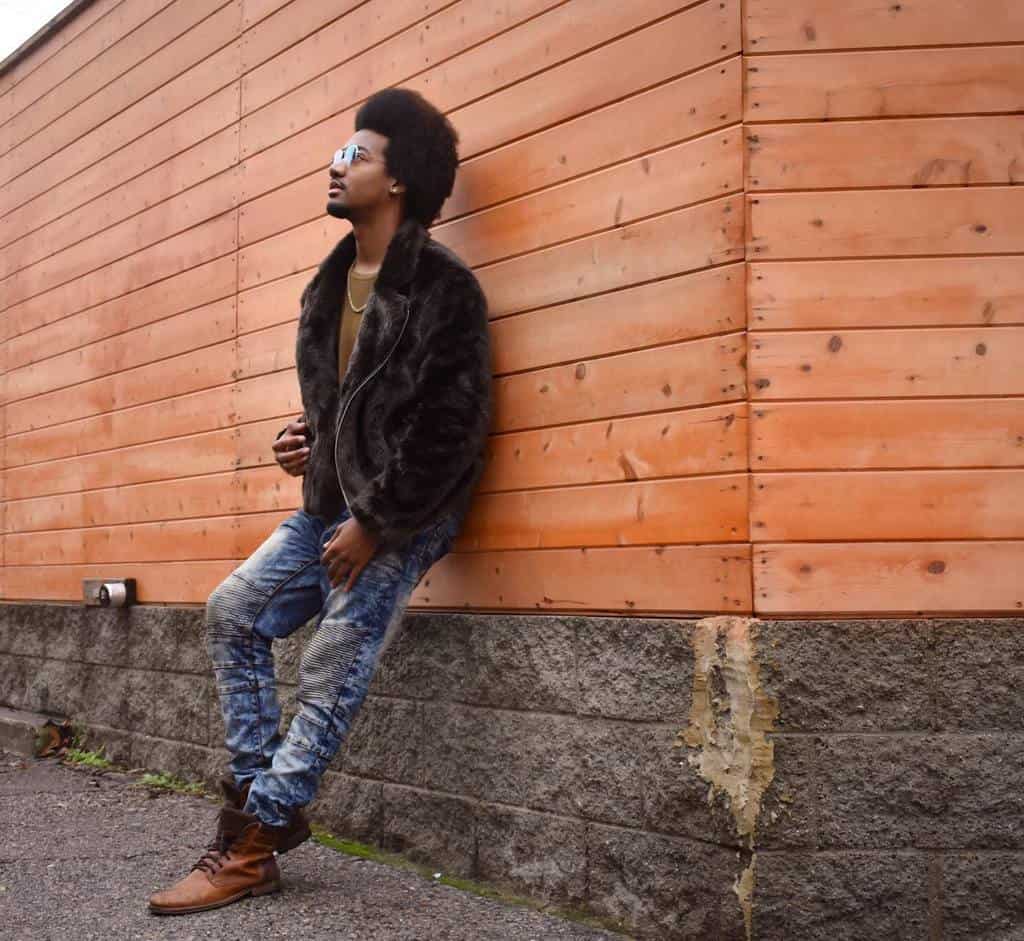 afro man wearing fur jacket under brown shirt denim pants 