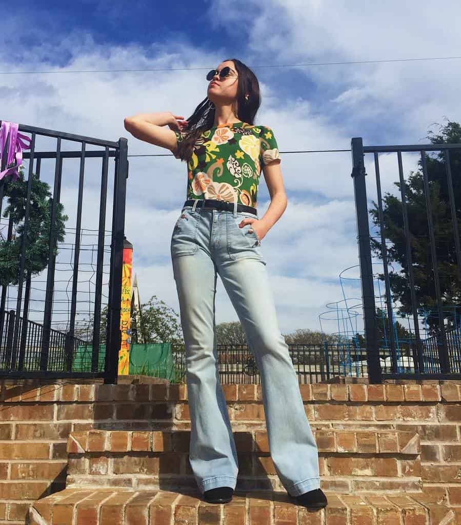 printed green shirt tuck in denim jeans with belt and cool shades