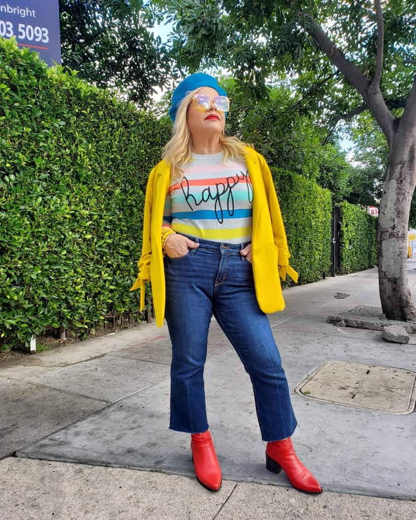 girl in printed colored shirt yellow jacket blue cap and denim pants red boots