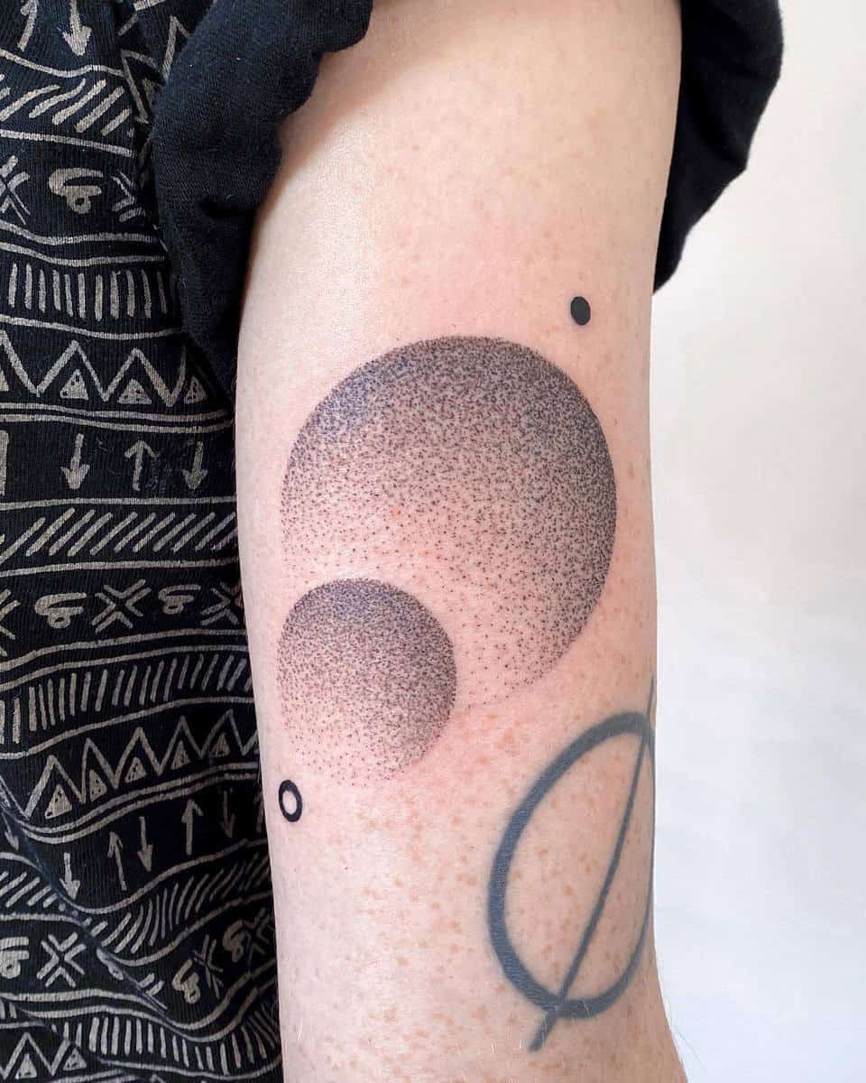Tattoo with two shaded circles and small dots on an arm